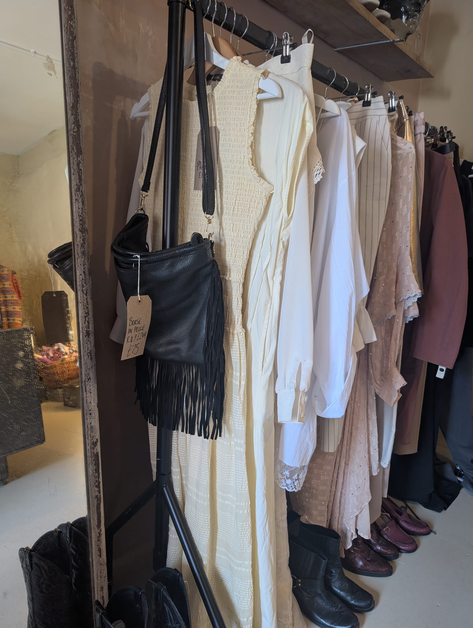 Cream and ivory dresses on the rail with a fringed black leather bag