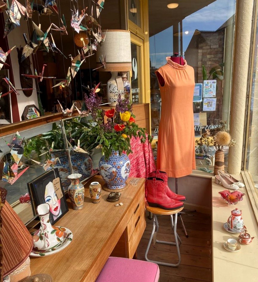 Beetle Eyes window display — orange dress, red cowboy boots, ceramics and origami cranes